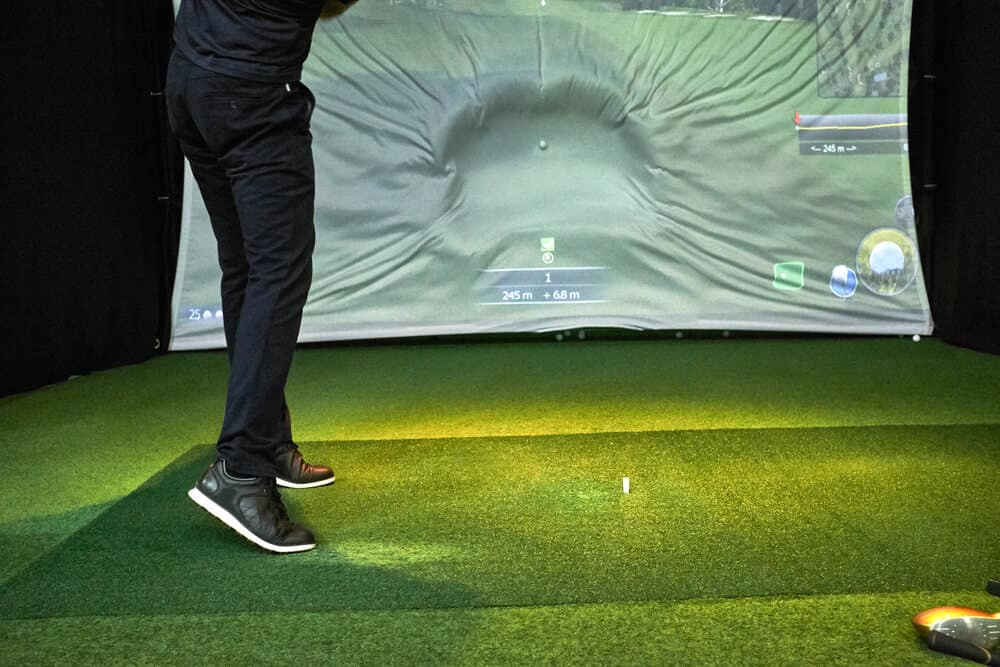 Man Hitting a Golf Ball in Virtual Screen Projector Golf Simulator